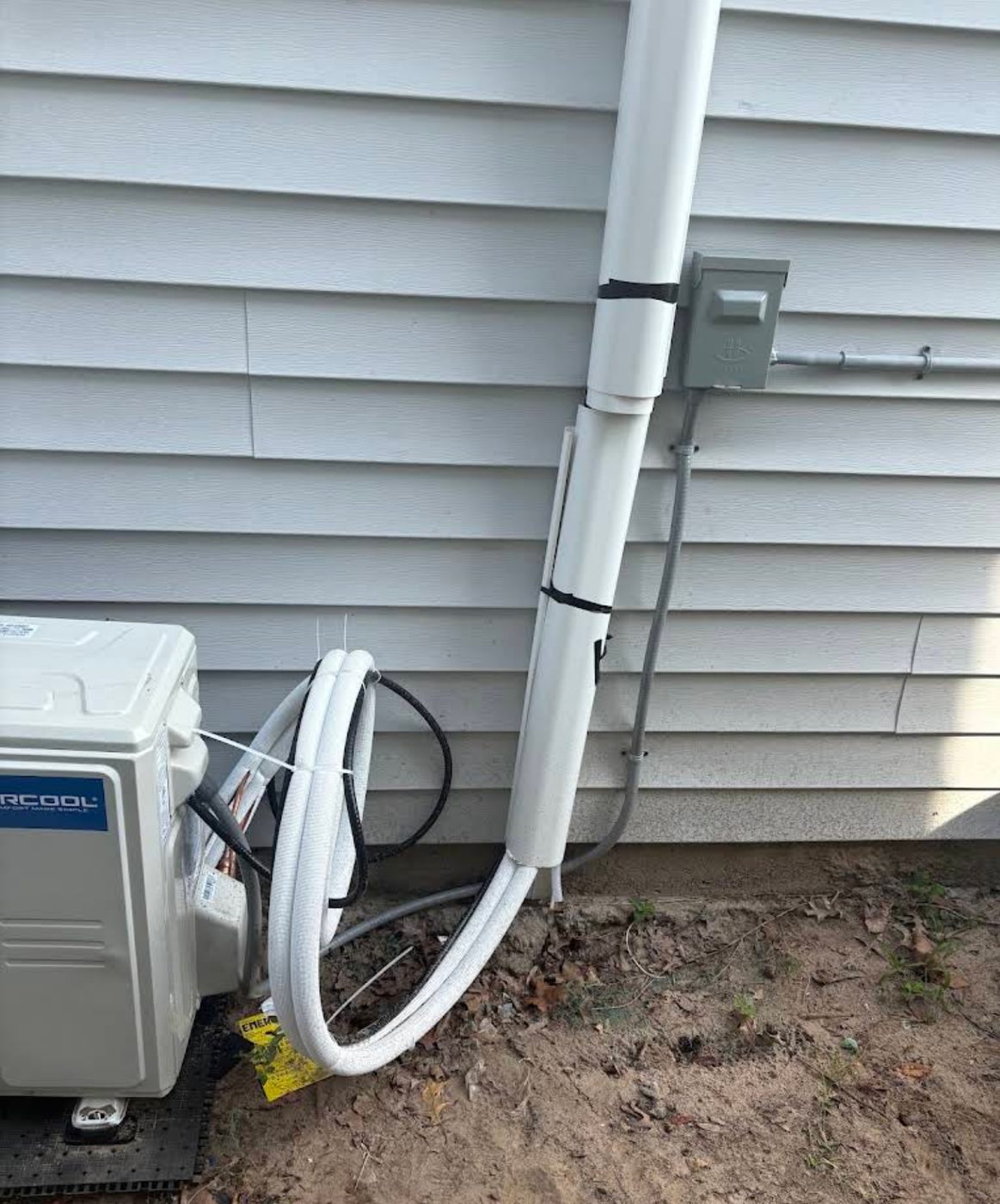 Exterior wall with a new conduit run and disconnect box feeding a ductless mini-split condenser